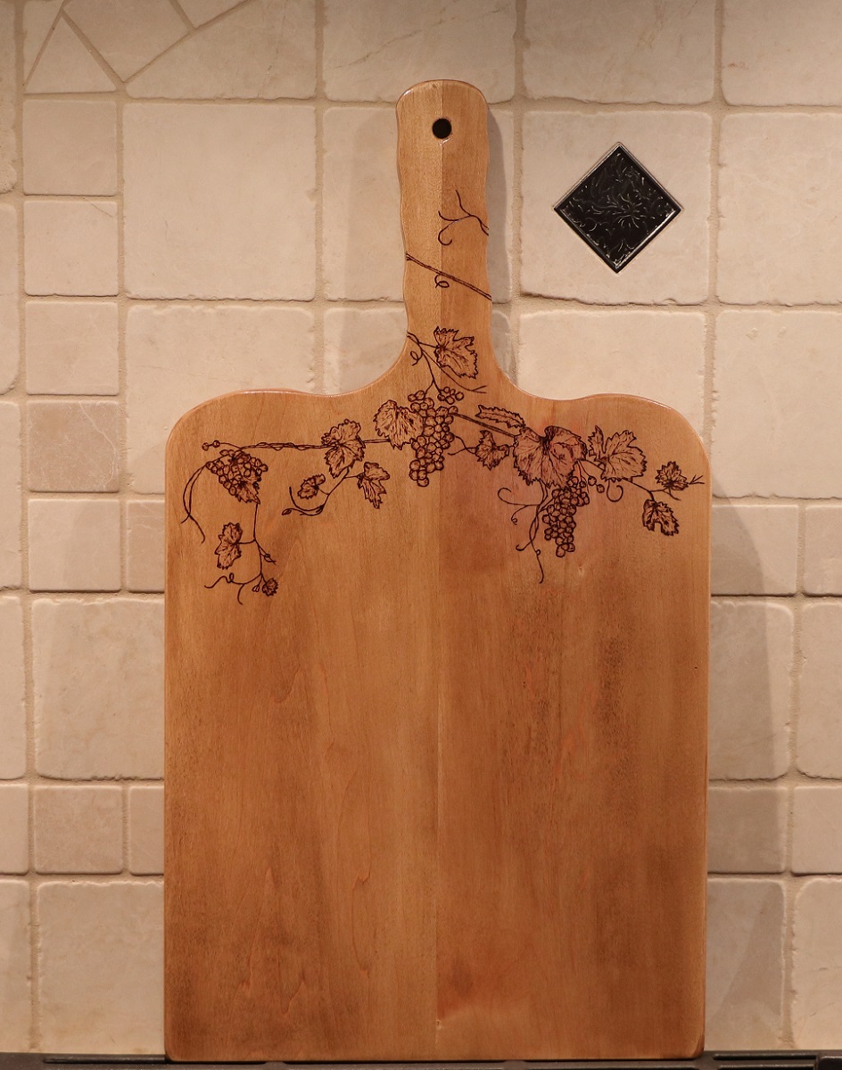 maple charcuterie board with woodburned grapevine