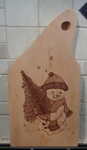 Snowman holding a christmas tree woodburned into a maple charcuterie board