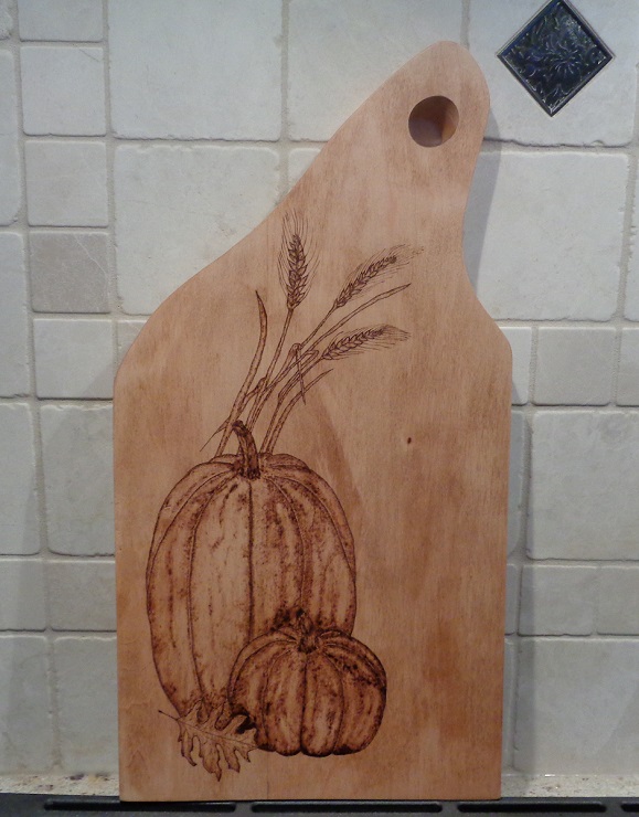 Snowman holdiong a christmas tree woodburned into a maple charcuterie board