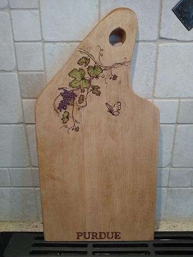 Woodburned grapes, grapevine, leaves and butterfly on a maple charcuterie board