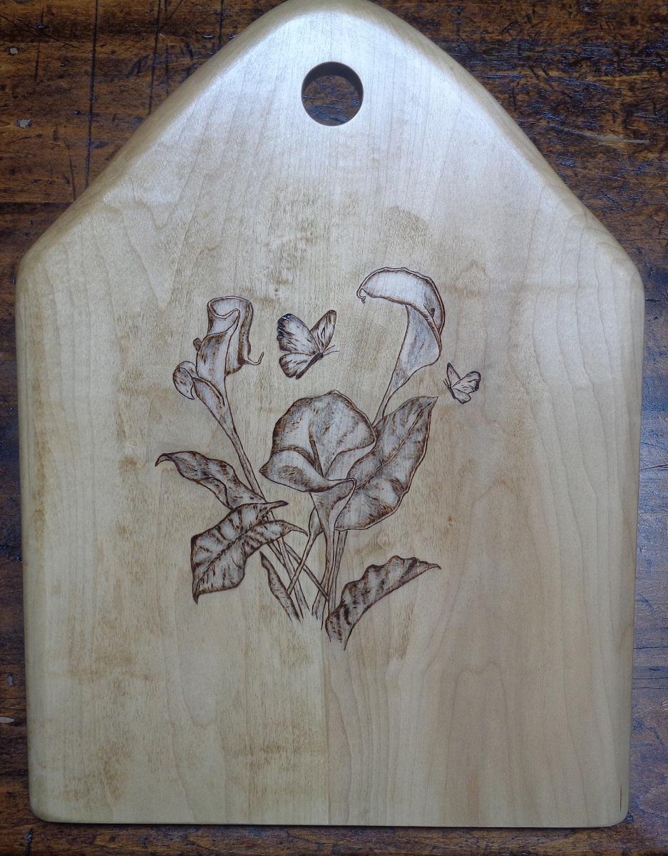 charcuterie board with woodburned limages of calla lily and butterflies