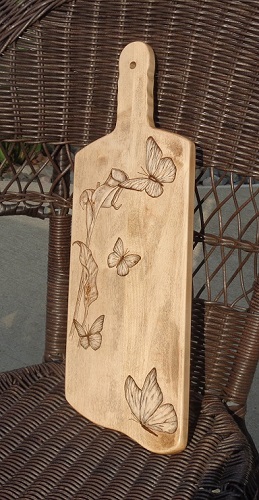 Calla lily and butterflies woodburned into a maple charcuterie board