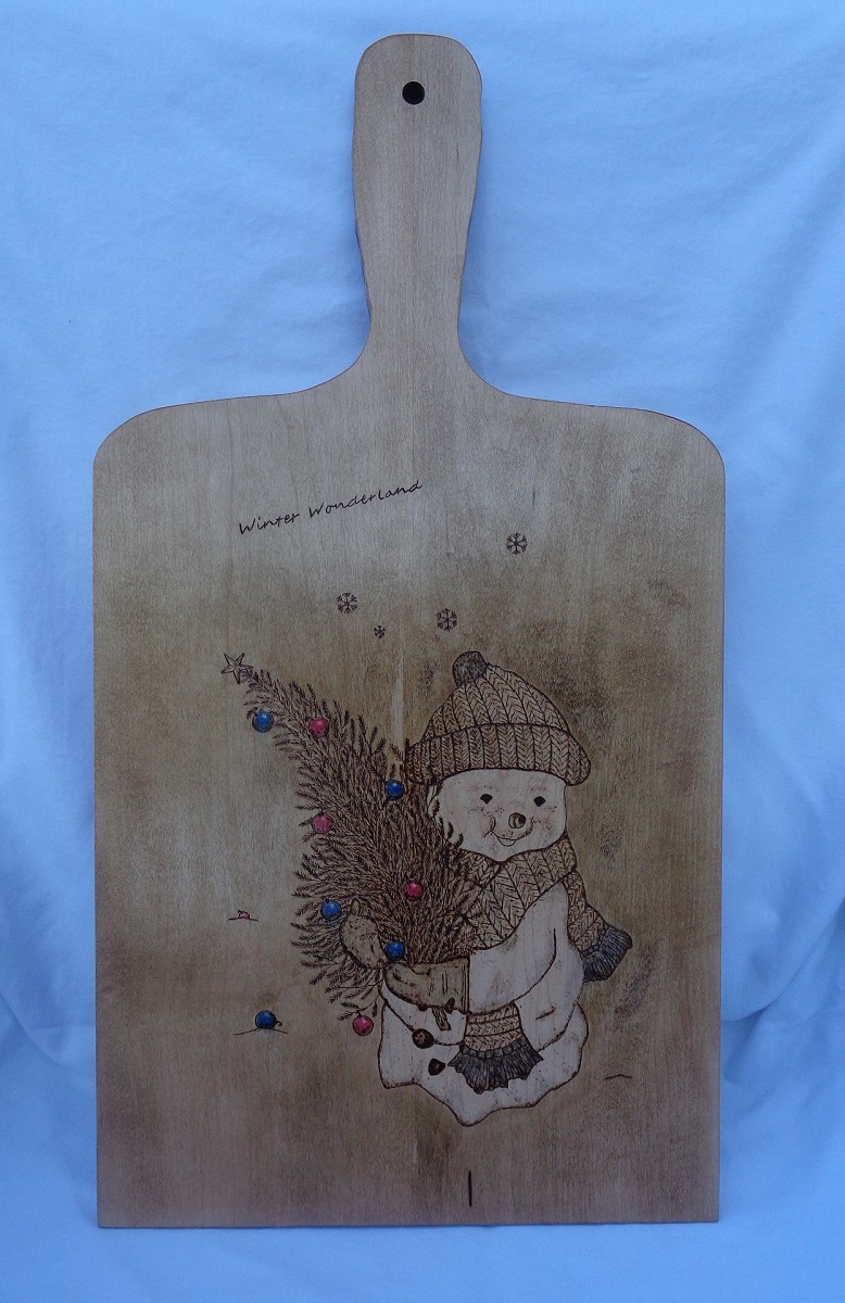 charcuterie board with woodburned limages of a Snowman carrying a Christmas tree