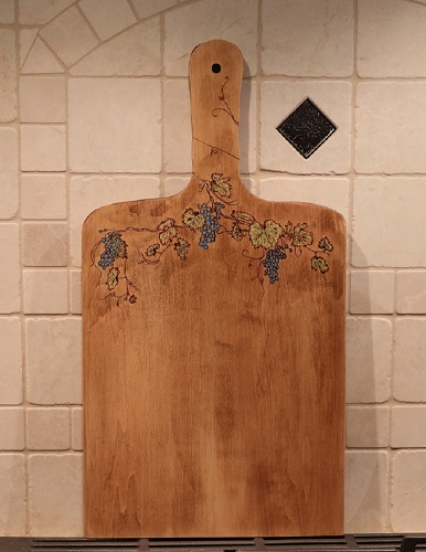 Woodburned grapes, grapevine and leaves on a maple charcuterie board