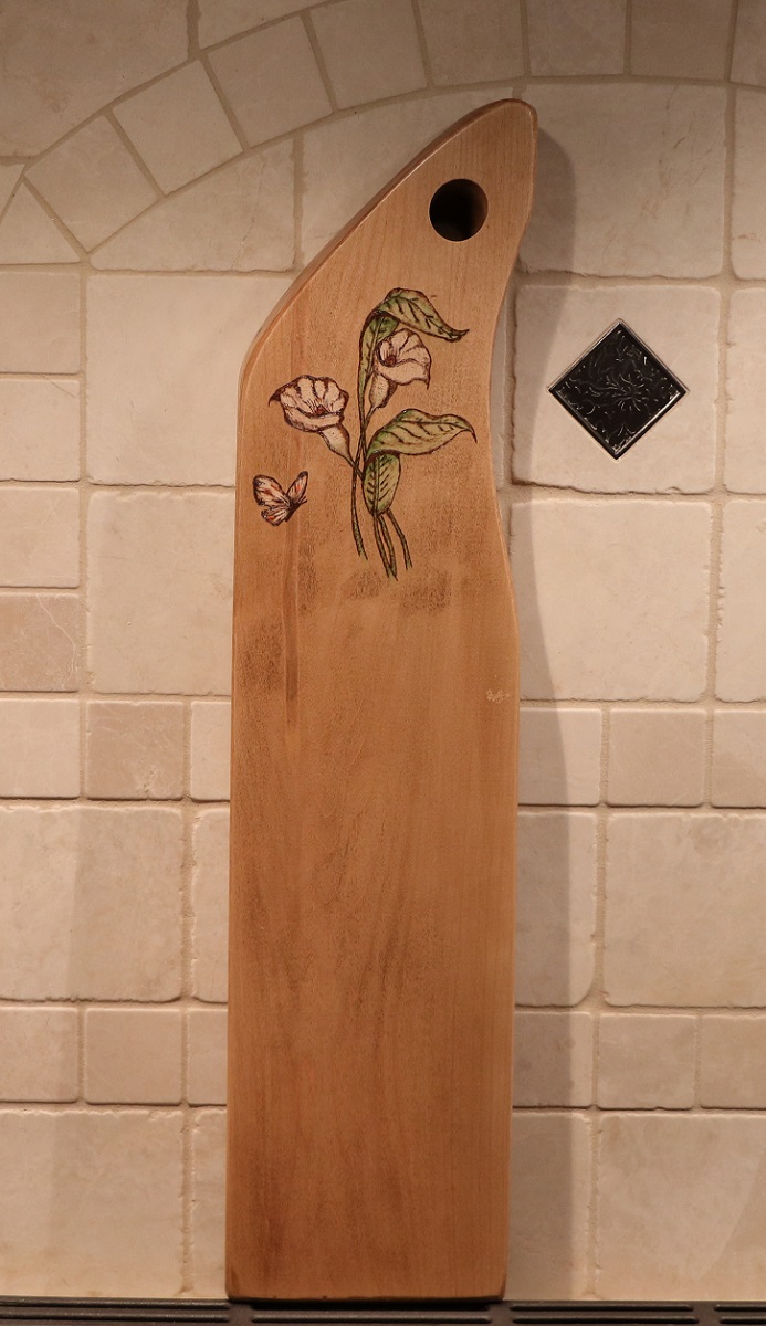 Calla lily and butterfly woodburned into a maple charcuterie board